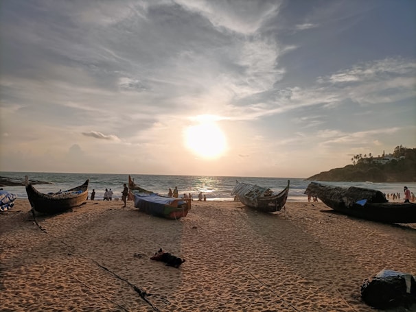 A peaceful beach with crystal clear water and traditional fishing boats at sunset.
