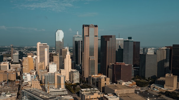 Aerial view of a modern city skyline with diverse buildings under a clear sky.