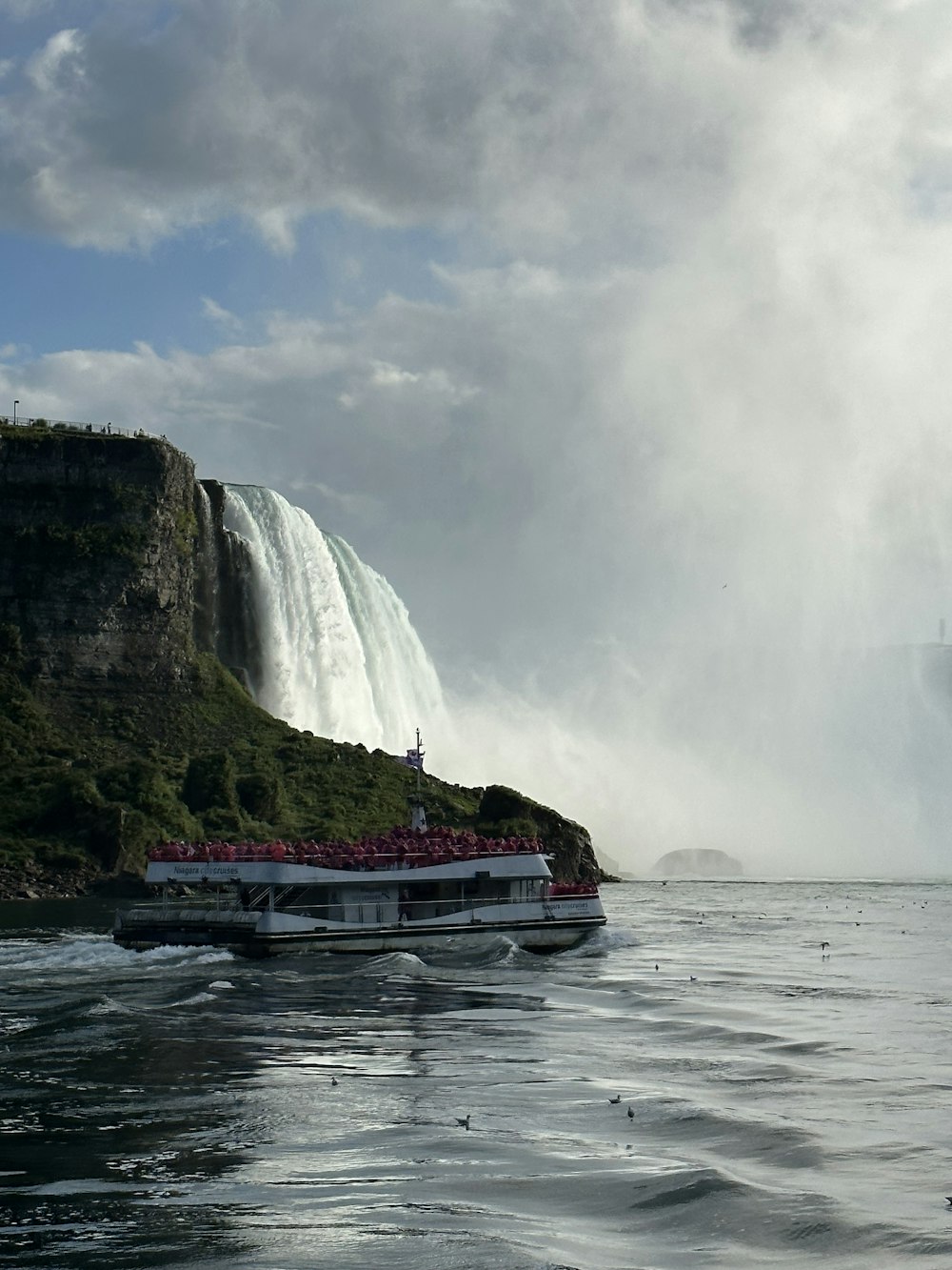 a boat in the water near a large waterfall