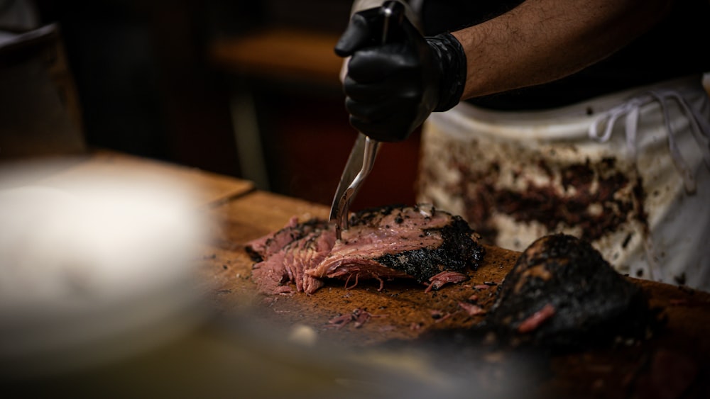 a person cutting a piece of meat with a knife