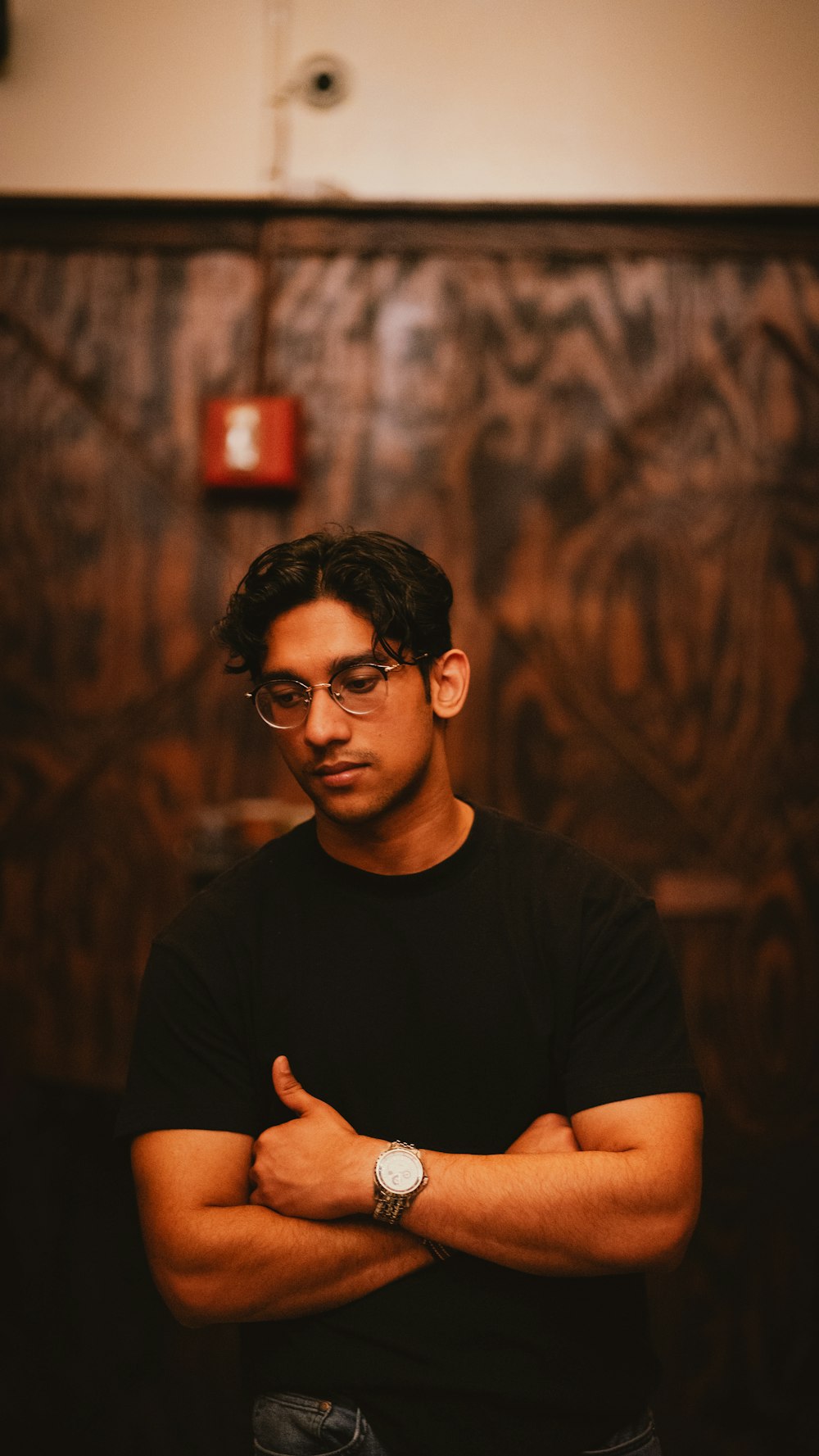 a man with glasses standing with his arms crossed