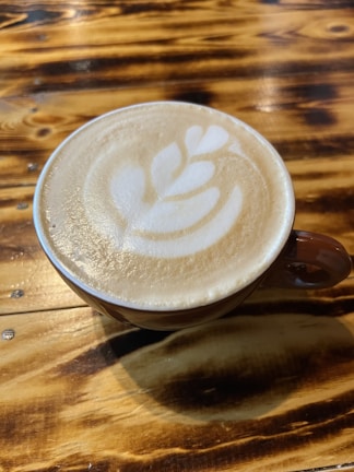 A cup of coffee featuring a heart-shaped foam design on a wooden table.