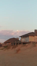 A serene Galveston beach house with soft pastel colors and a wooden porch overlooking the ocean at sunset.