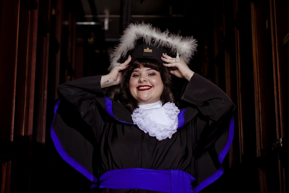 a woman in a graduation gown holding her hat over her head