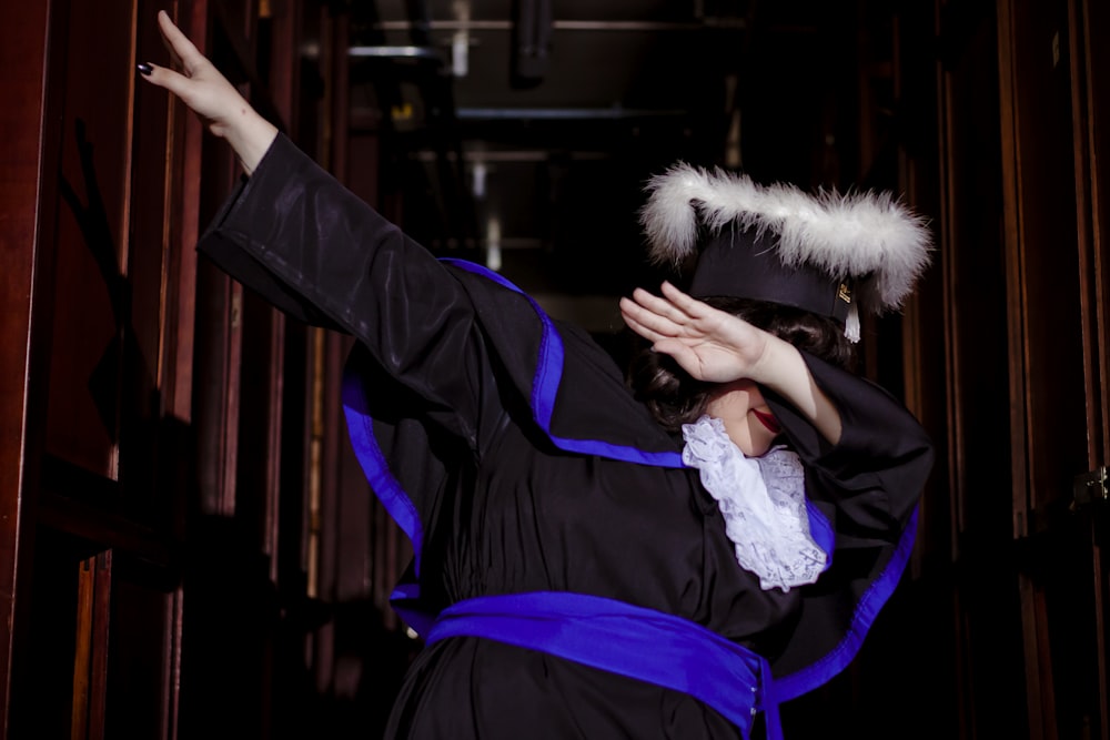 a woman dressed in a graduation gown and holding her hands up