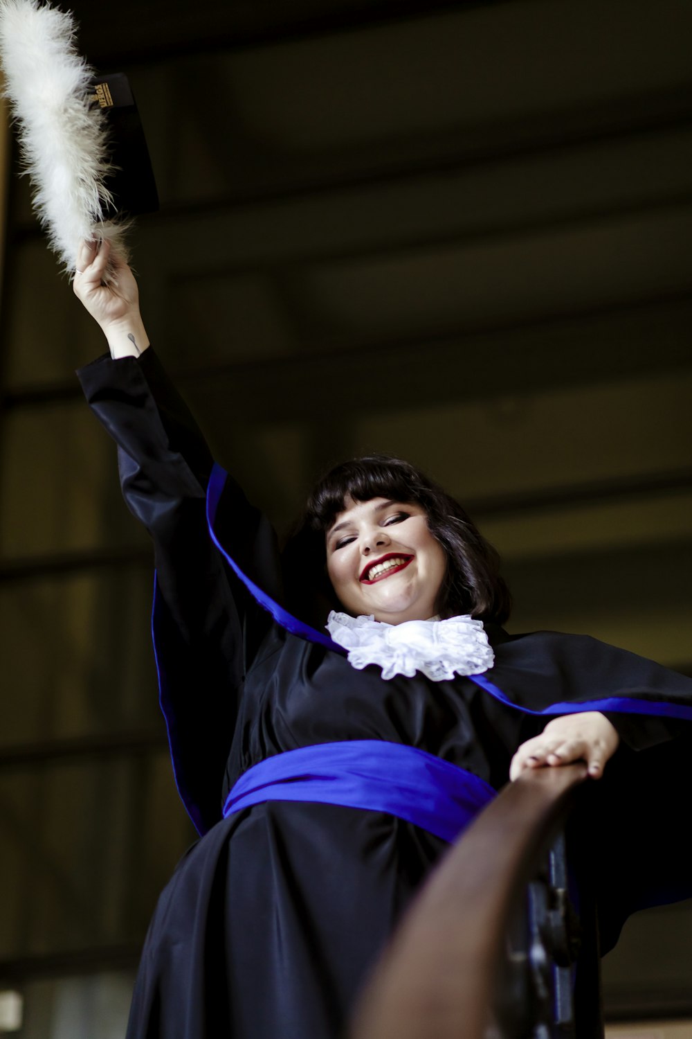 a woman in a graduation gown holding a feather