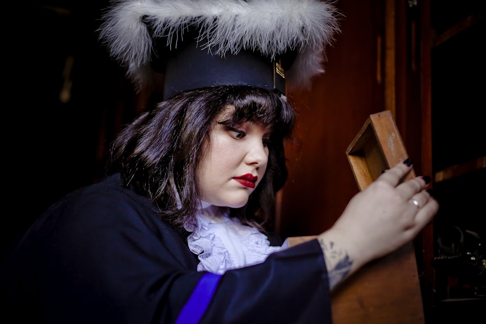 a woman in a graduation gown holding a wooden box
