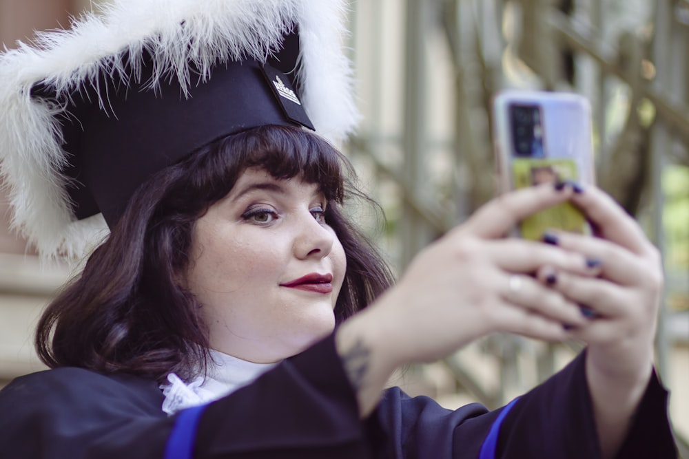 a woman in a graduation gown taking a picture with her cell phone