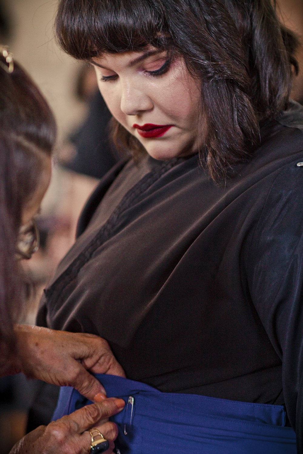 a woman in a black dress is cutting another woman's hair