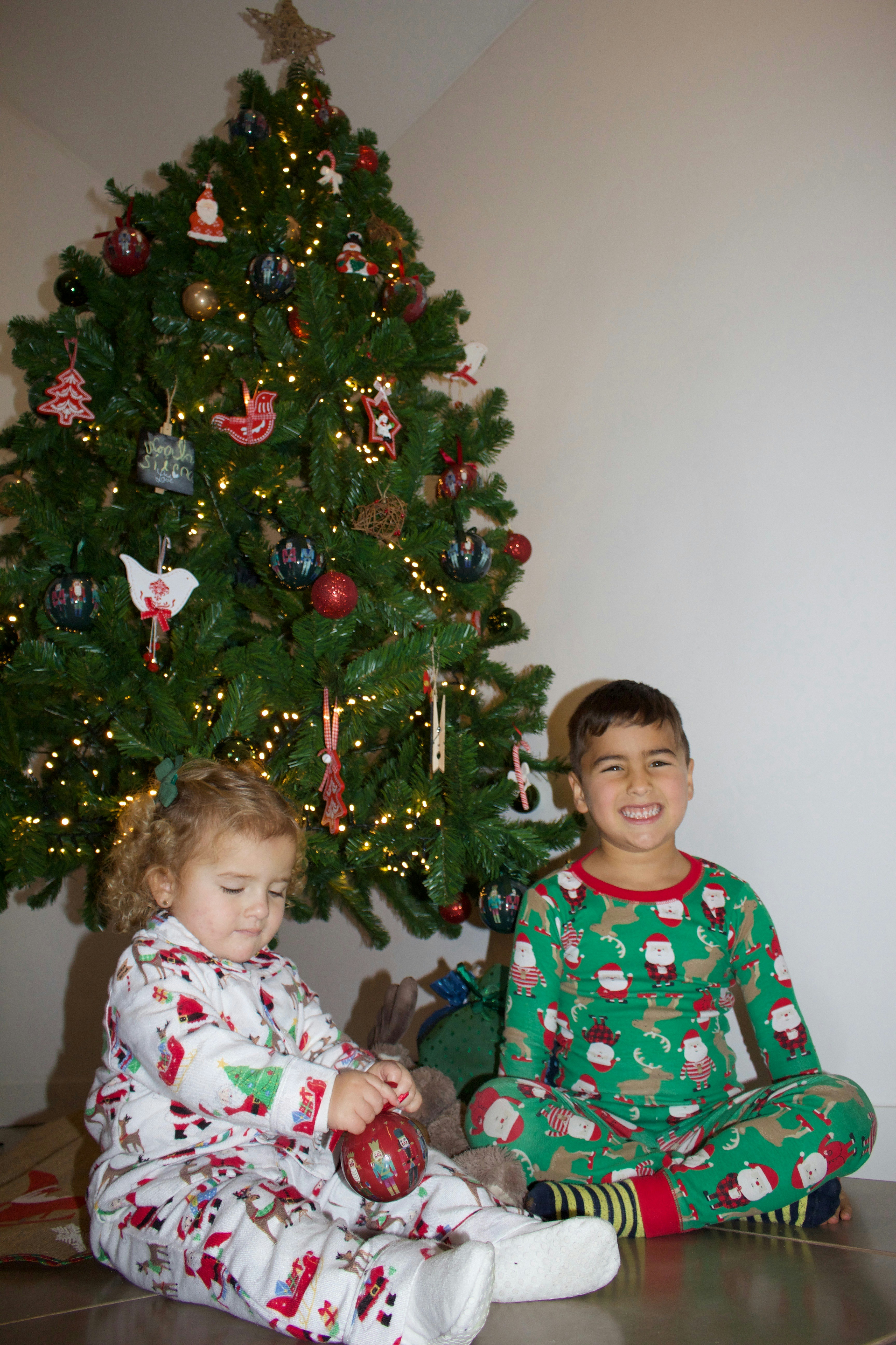 two children sitting in front of a christmas tree