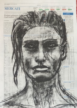 A charcoal drawing of a human face is superimposed over a page of a newspaper filled with text and numbers. The portrait features defined facial features, including intense eyes and a slightly parted lip expression. The background text is visible through the strokes of the charcoal drawing, adding a layered effect.