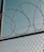 Barbed wire is coiled above a metal chain-link fence, with a clear sky in the background. The image conveys a sense of security and restriction.
