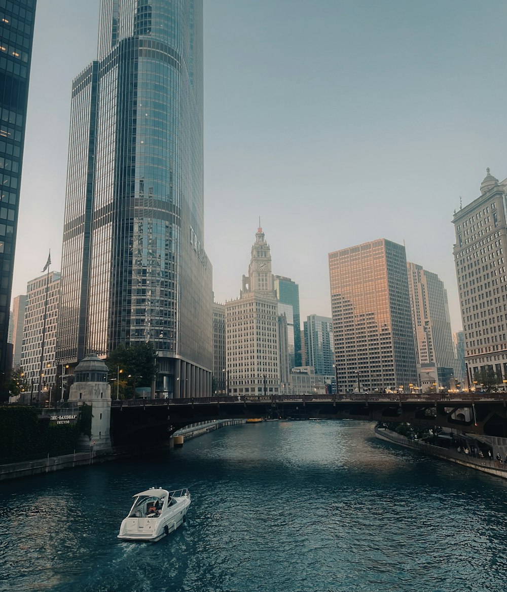 a white boat traveling down a river next to tall buildings