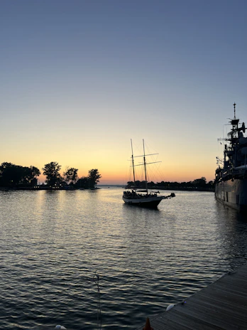 Sleek Dutch-designed sailing yacht gliding over calm blue waters at sunset.