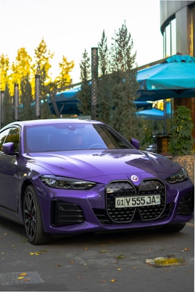 A sleek, modern car parked beside a confident influencer smiling warmly, set against a vibrant purple and green backdrop.