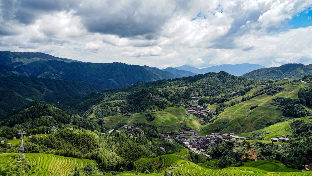 a lush green valley surrounded by mountains under a cloudy sky