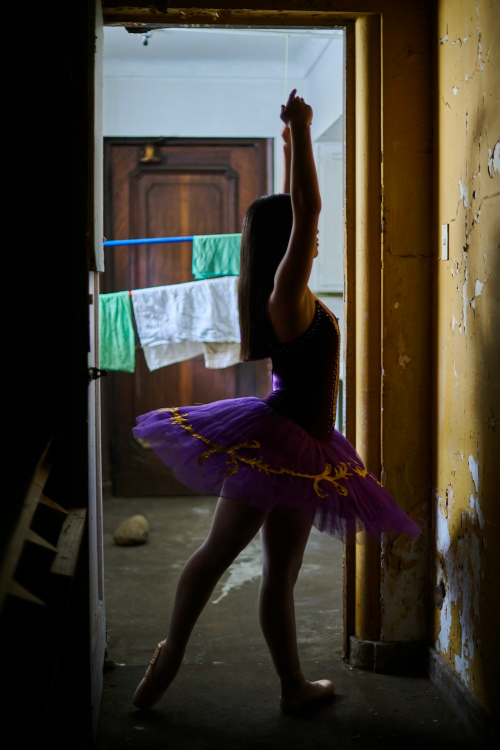 a woman in a purple tutu dancing in a doorway