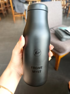 a person holding a black bottle in their hand
