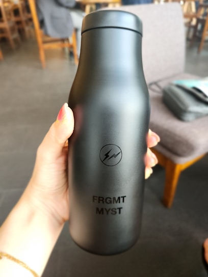 a person holding a black bottle in their hand