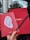 A hand with red nails holds two red Cartier envelopes, one featuring an oval-shaped sticker with the words 'TIME UNLIMITED'. A black Cartier pen is also held between the fingers. The background shows a view through a car window, revealing buildings and trees.