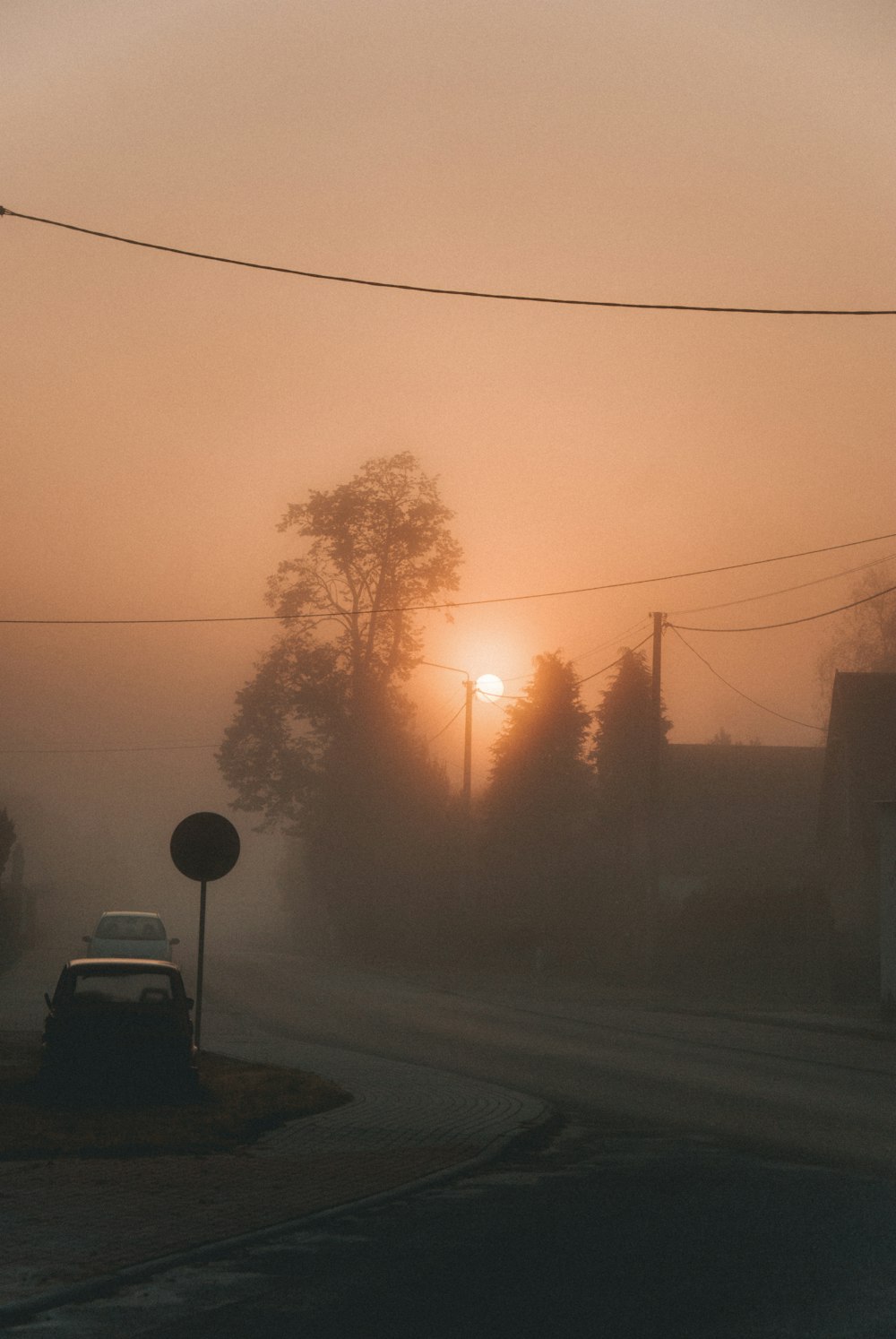 a foggy street with a car parked on the side of the road