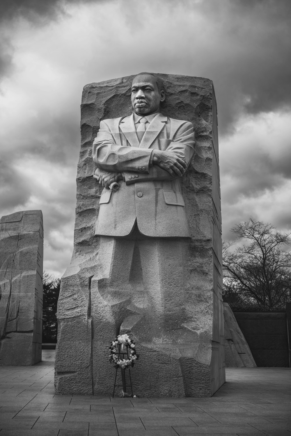 a black and white photo of a man standing in front of a statue