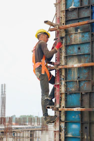 A construction site supervisor inspecting a building with yellow safety gear.