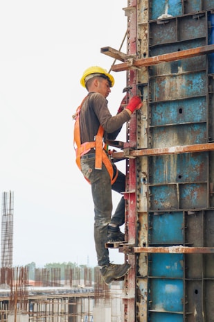 A construction worker in a hard hat inspecting a building site with tools in hand.