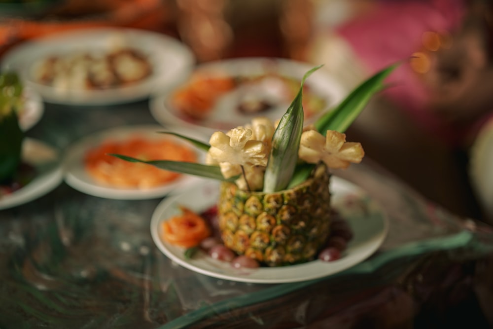 a table topped with plates of food and a pineapple