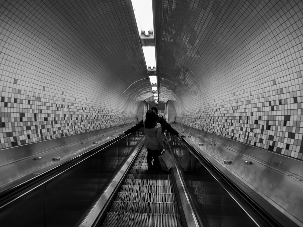 a person riding an escalator down a tiled wall