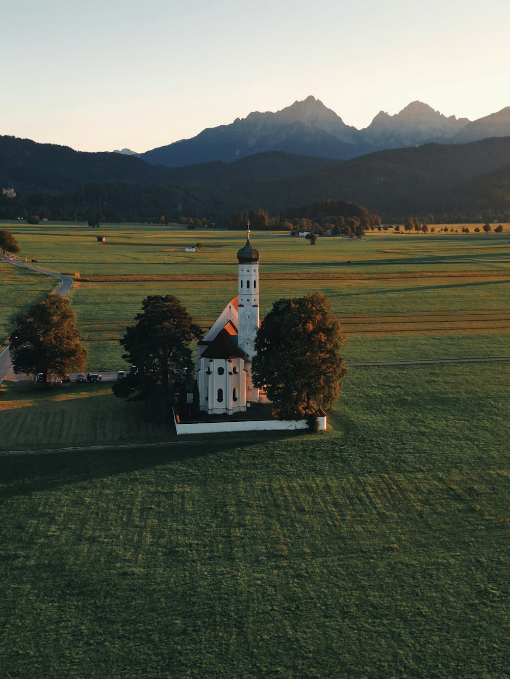 uma igreja no meio de um campo com montanhas ao fundo