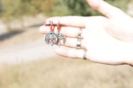 Earrings shaped like tiny starfish, shimmering softly in the sunlight against a turquoise ocean backdrop.