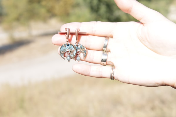 Close-up of handcrafted silver earrings with turquoise stones resting on a rustic wooden surface.