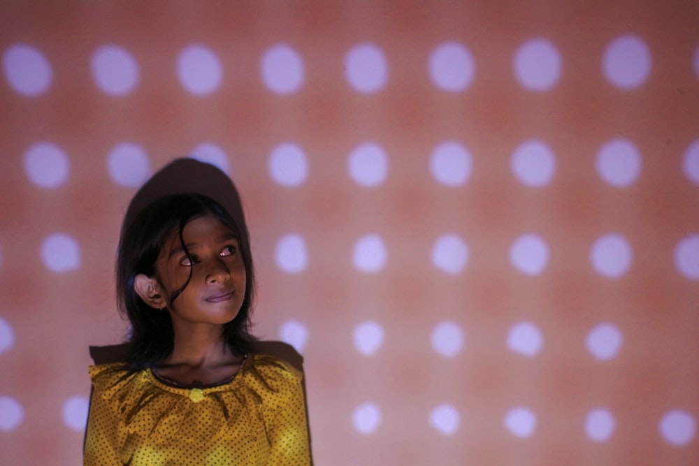 a woman standing in front of a wall with dots on it