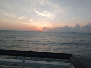 A serene sunset view over the ocean with a yacht in silhouette.