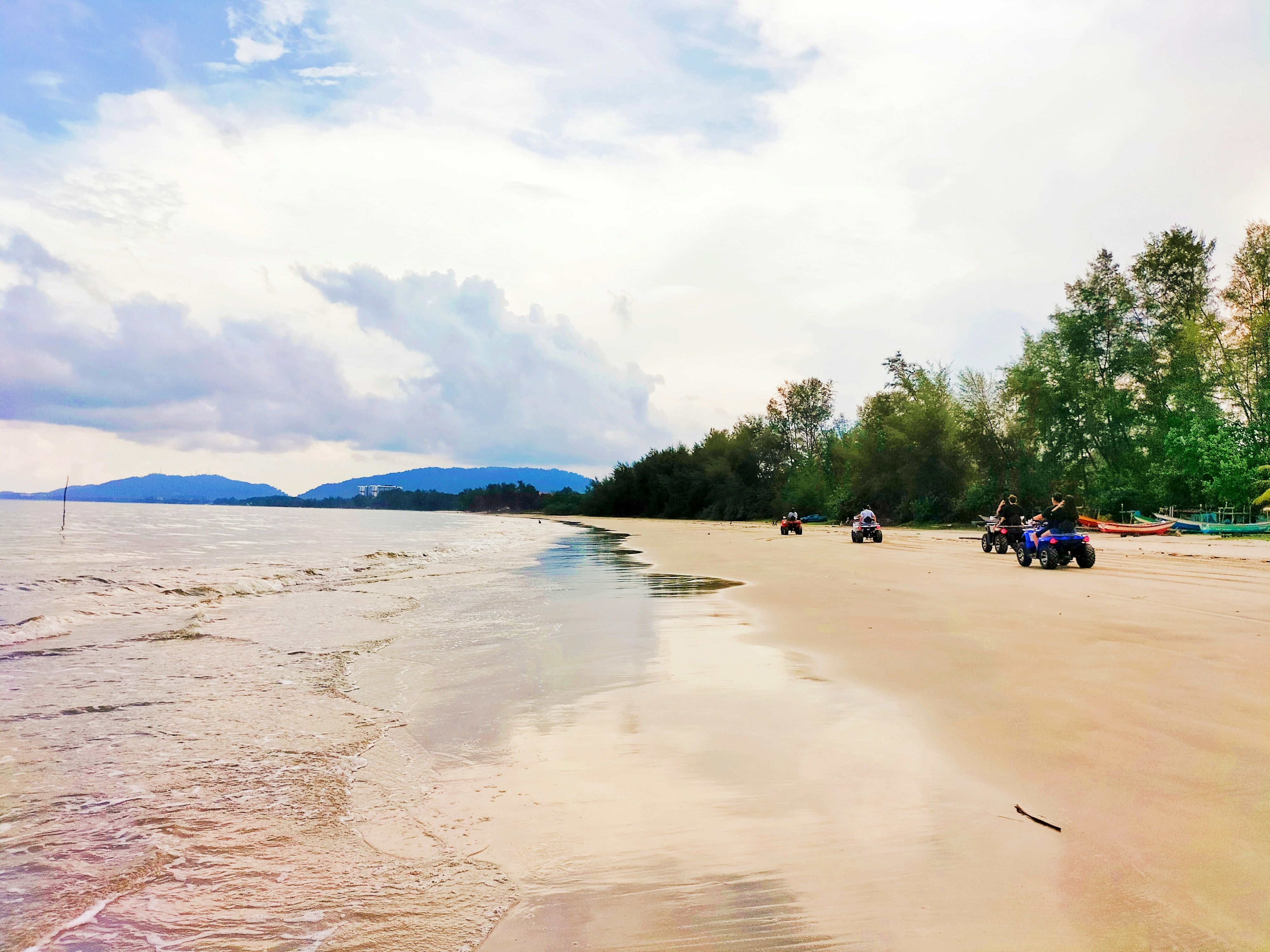 a group of people riding four wheelers on a beach