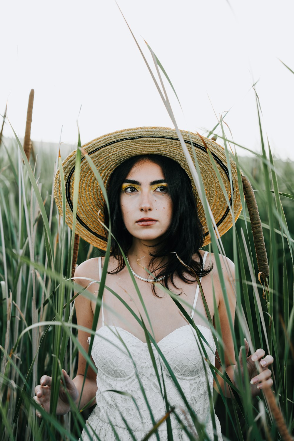 a woman wearing a straw hat standing in tall grass