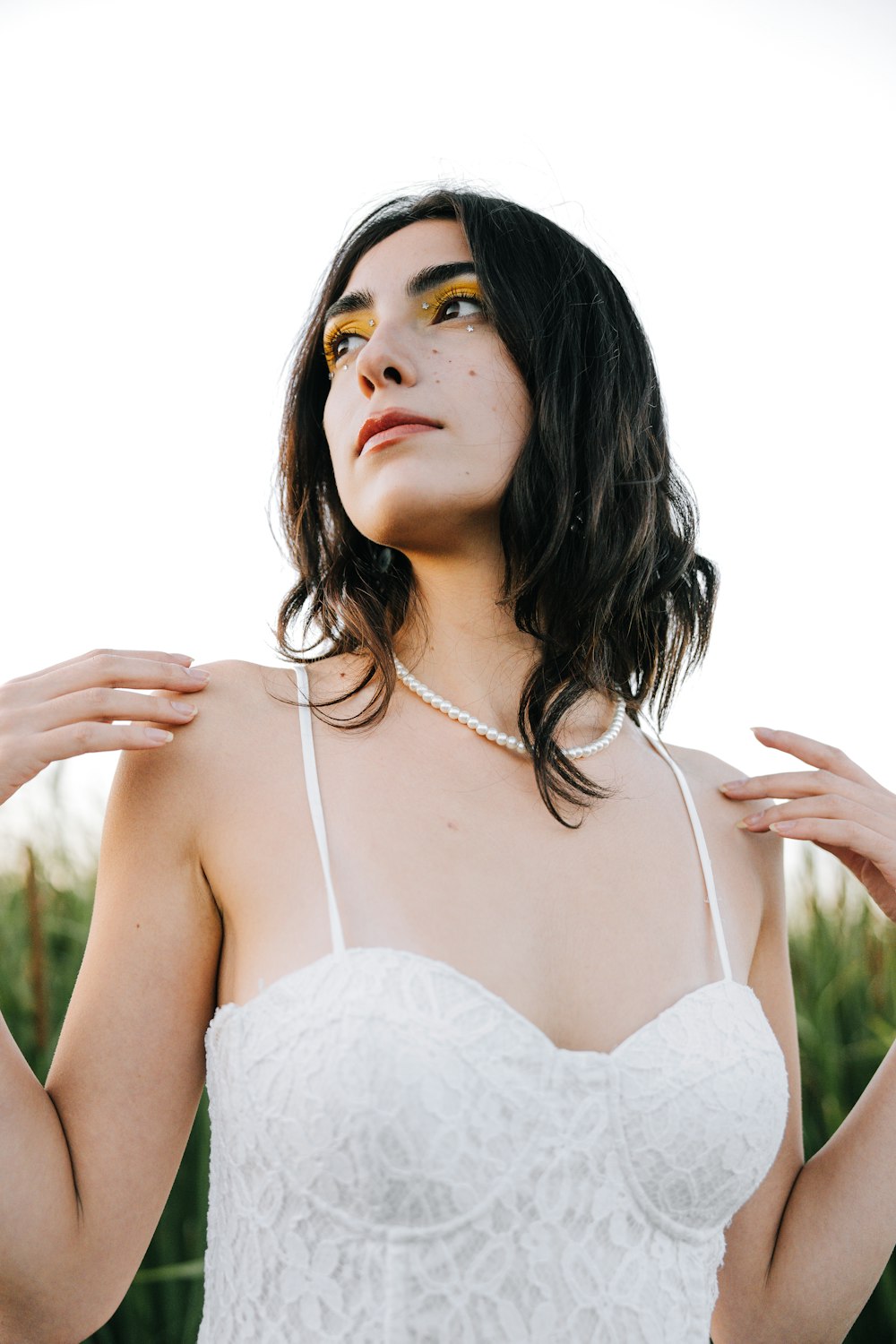 a woman wearing a white dress and a pearl necklace