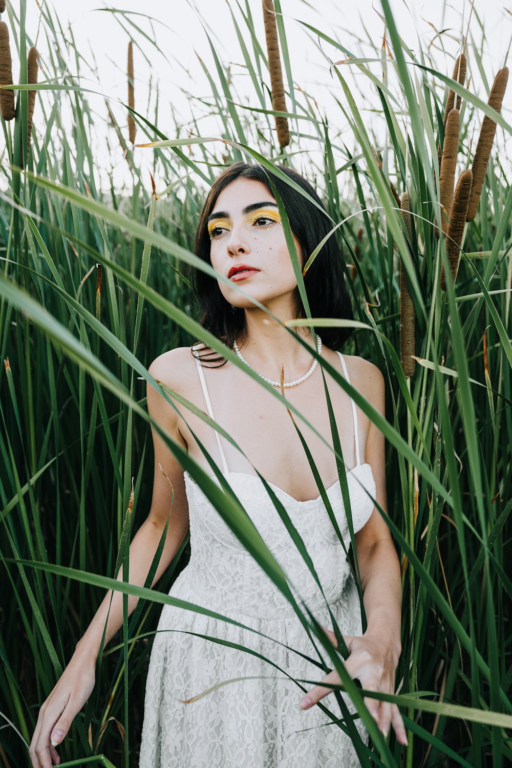 a woman in a white dress standing in tall grass