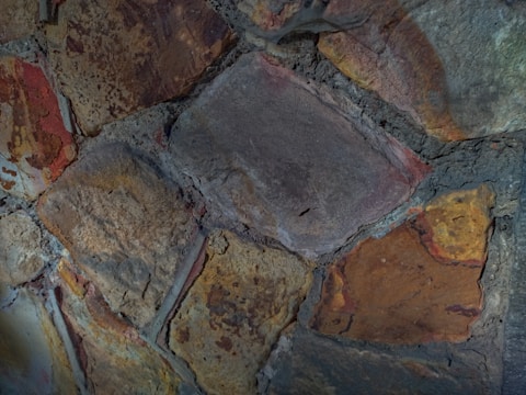 Close-up of a rustic stone wall with varied textures and warm earth tones.