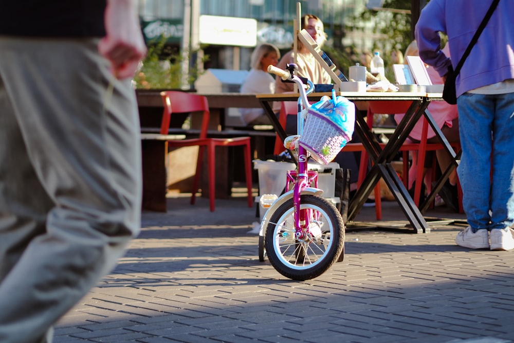 a little girl riding a pink bike down a sidewalk