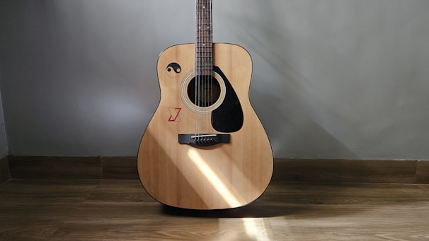 Close-up of a beginner acoustic guitar resting on a cozy wooden floor with soft natural light.
