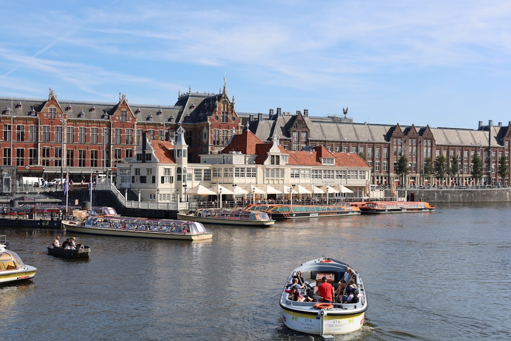 a group of boats floating on top of a river next to tall buildings