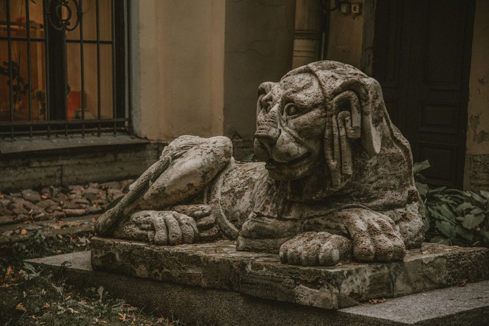 Una estatua de un león acostado frente a un edificio