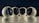 Four spherical security cameras with a glossy white finish are positioned in a row, each featuring a prominent lens and the brand name 'Briton' visible on their bases. The background is dark, contrasting with the brightly lit cameras.