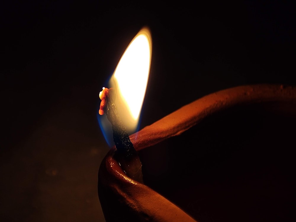 a lit candle in the dark with a dark background