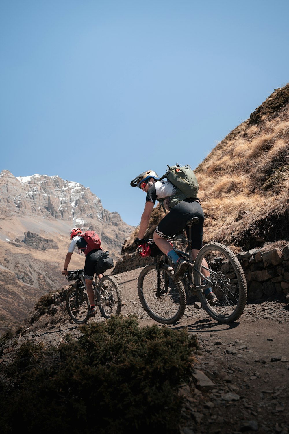 a couple of people riding bikes down a dirt road