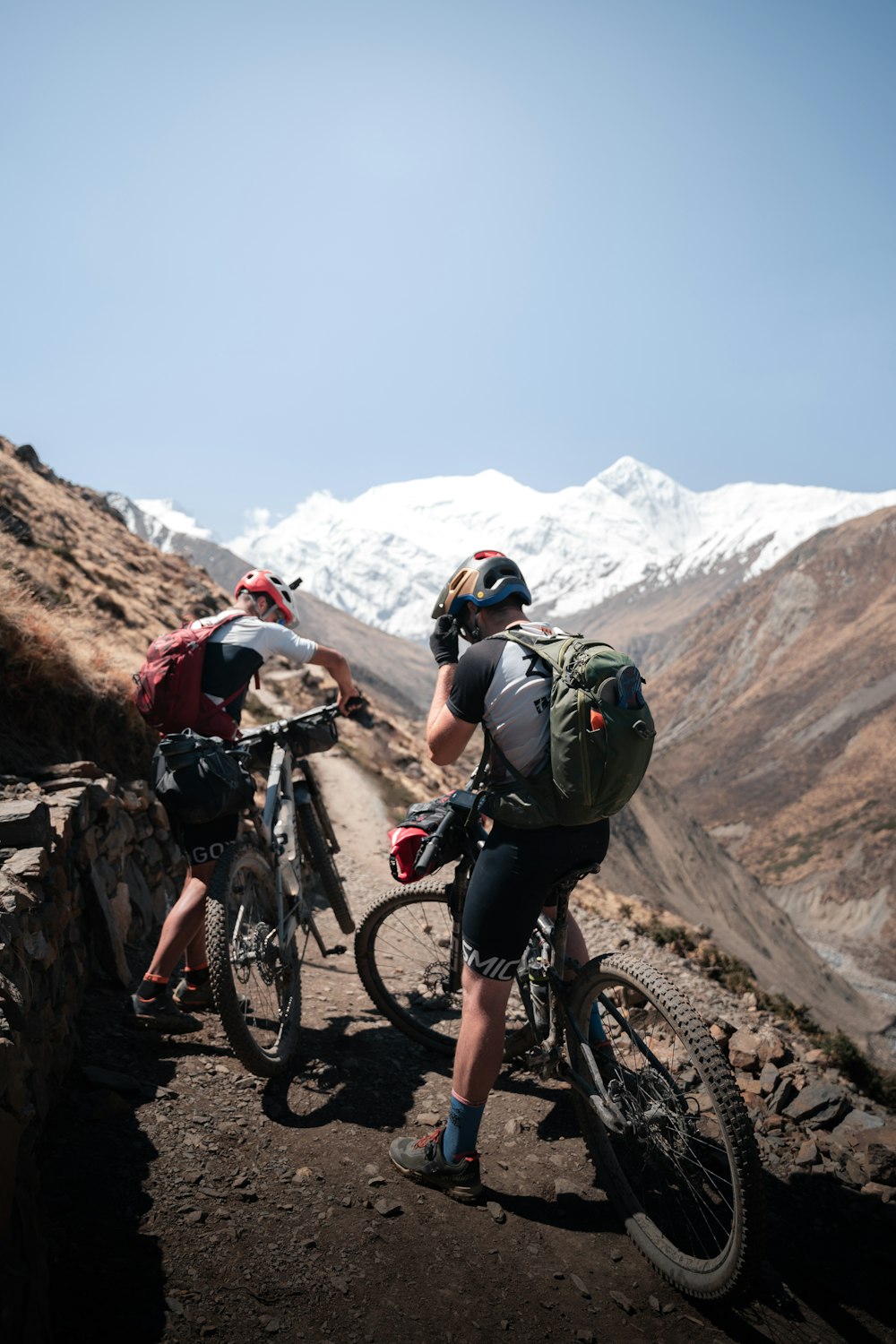 a couple of people riding bikes on a dirt road