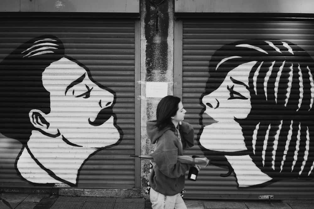 a woman walking down a street past a garage door