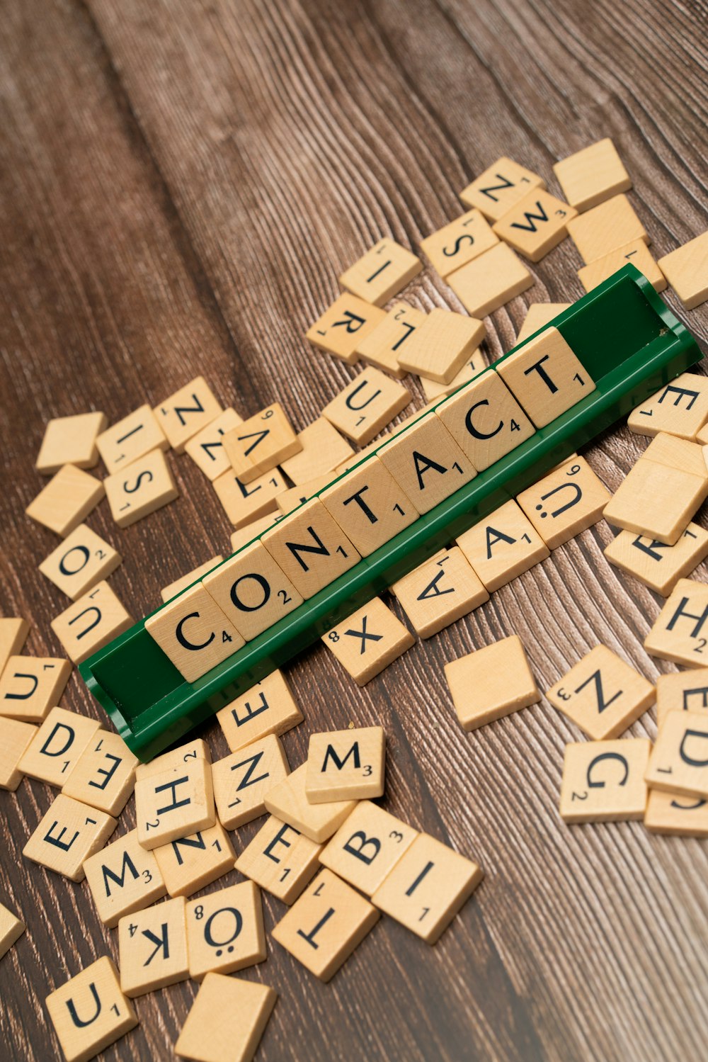 scrabble tiles spelling out contact on a wooden table